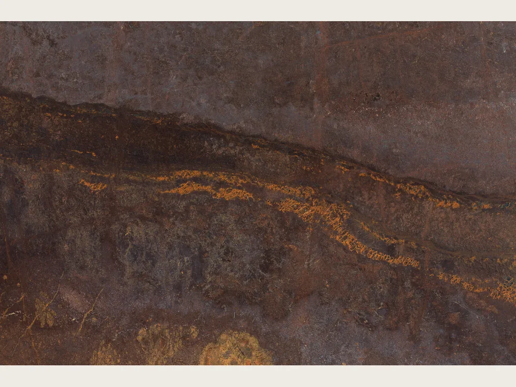 Bronzite quartzite slab: chocolate brown background with a darker horizontal band dotted with golden orange glints