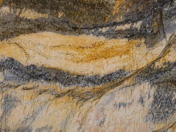 Close-up of Jacaranda quartzite: mustard and dark gray waves with the shine of polish