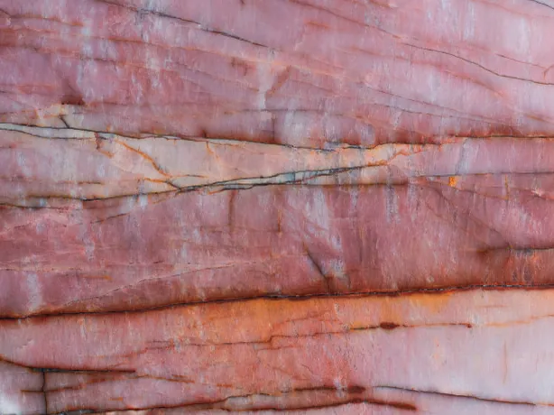 Close-up of pink Juliet quartzite: horizontal rust red and orange veins over the pink