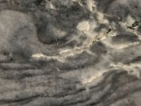Slab of London Grey Quartzite: charcoal grey with a network of cream veins and wavy dark bands