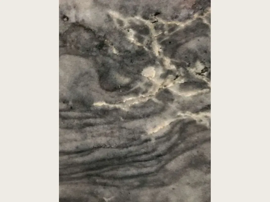Slab of London Grey quartzite: charcoal grey with a network of cream veins and wavy dark bands