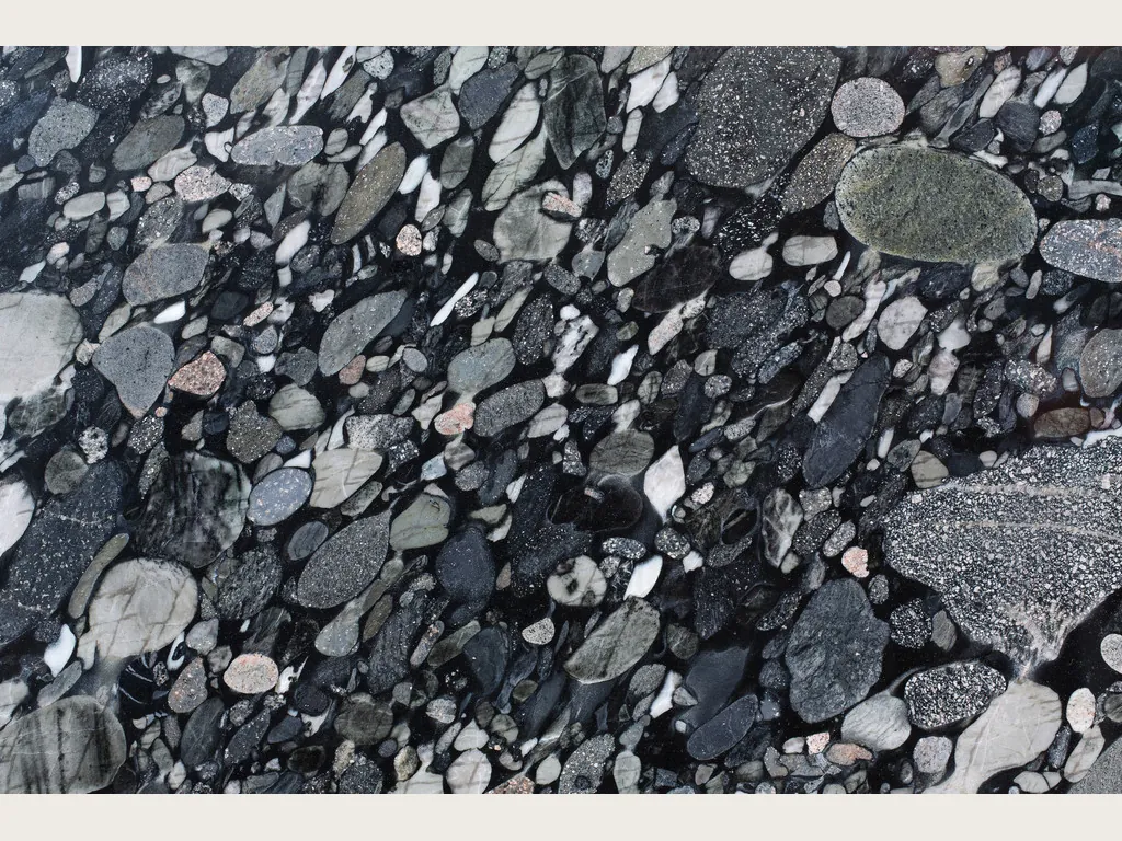 Slab of Marinace Black quartzite: gray, white and pink pebbles on a black background