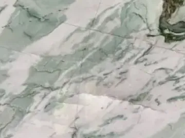 Close-up of green Tiffany Wow quartzite: dark green wavy veins with white strokes and the shine of the polish
