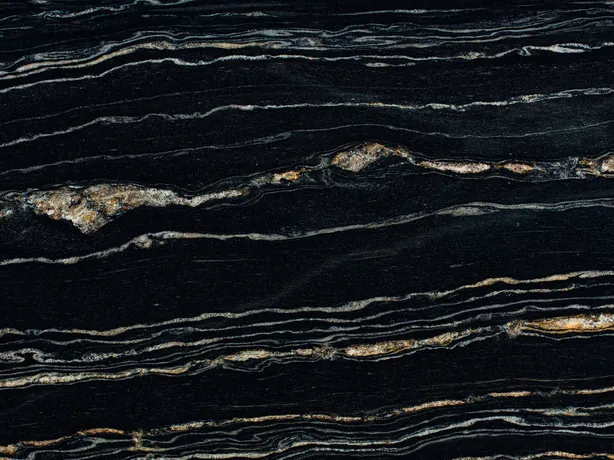 Close-up of Tropical Storm black quartzite: gold and white strokes on the polished black
