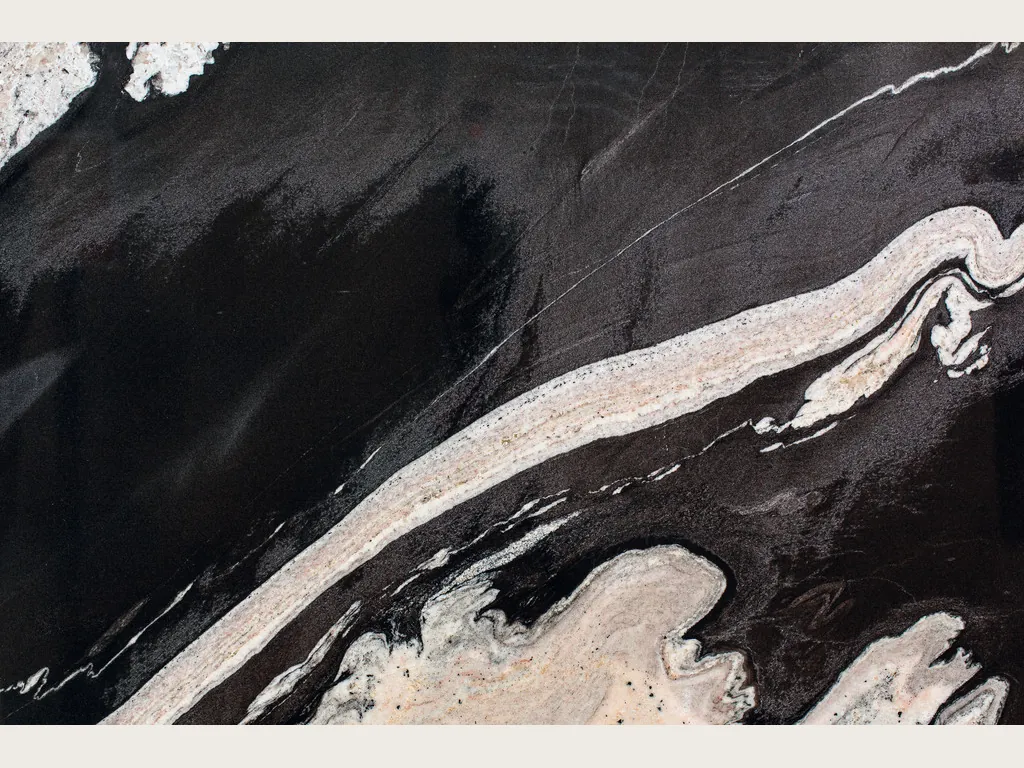 Black Copacabana granite slab: a wavy cream band on the diagonal over a black background, with cream patches at the edges