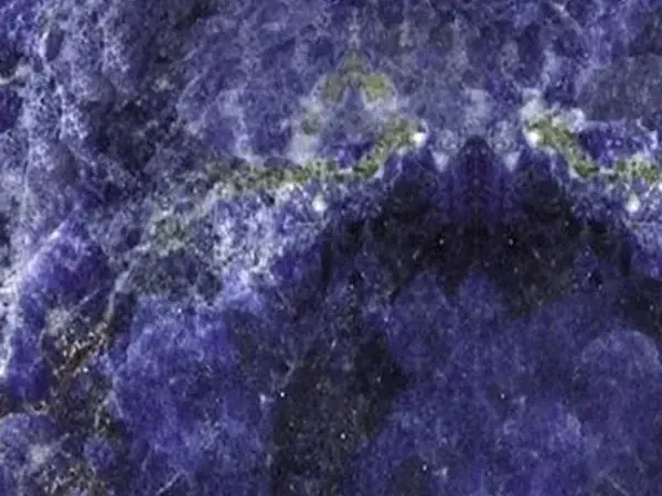 Jeriba Blue granite slab: intense violet blue with white clouds and a horizontal golden green line