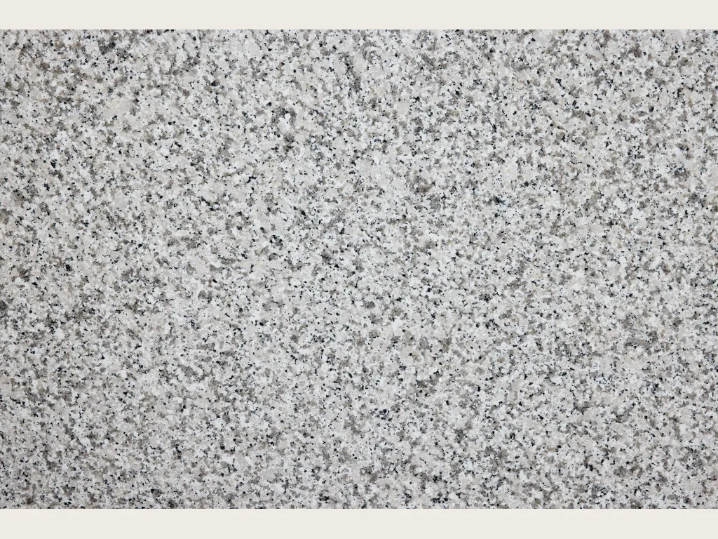 Slab of white Bianco Sardo granite: a coarse-grained grayish white background with gray and black crystals (another slab)