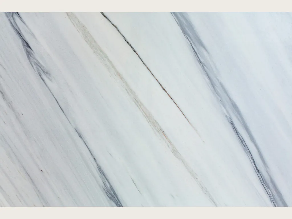 Slab of white Bianco Covelano marble: straight, parallel blue-gray veins on the diagonal over white