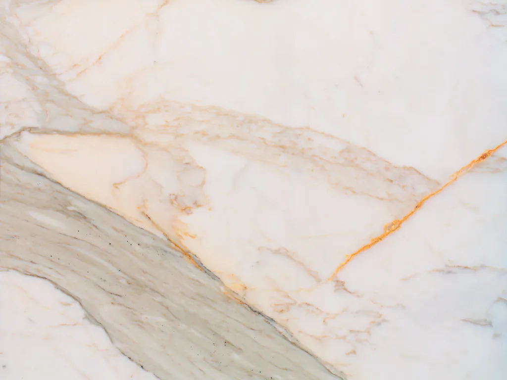 Calacatta Macchia Vecchia slab: wide diagonal beige gray band and fine golden veins over the warm white