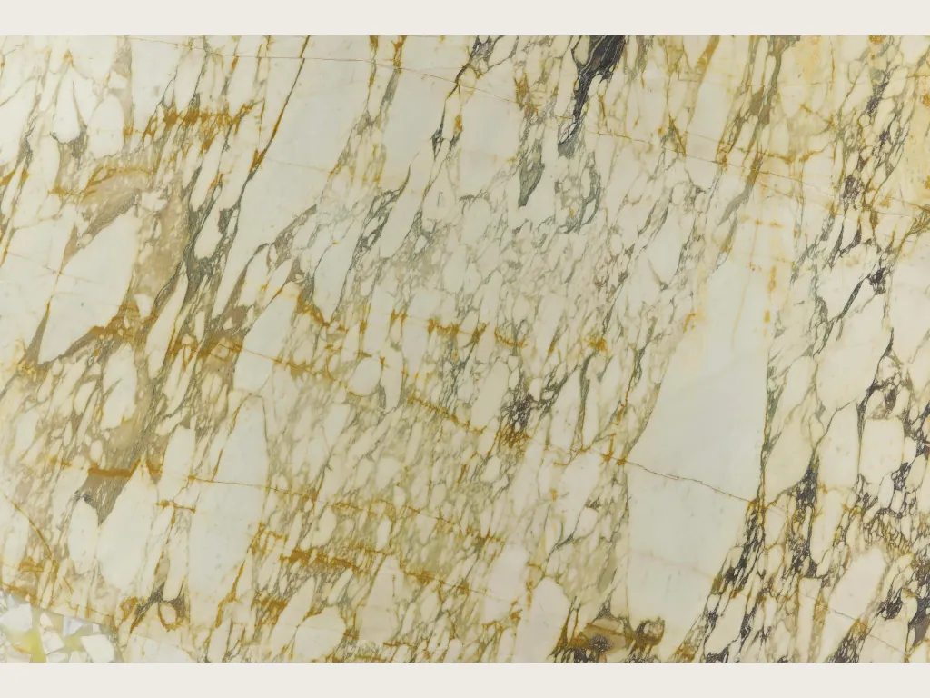 Slab of beige Calacatta Monet Gold marble: cream fragments inside a dense network of gold and dark gray veins