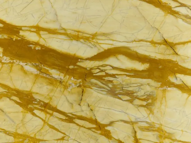 Calacatta Siena detail: thick ochre veins weaving over the pale yellow background