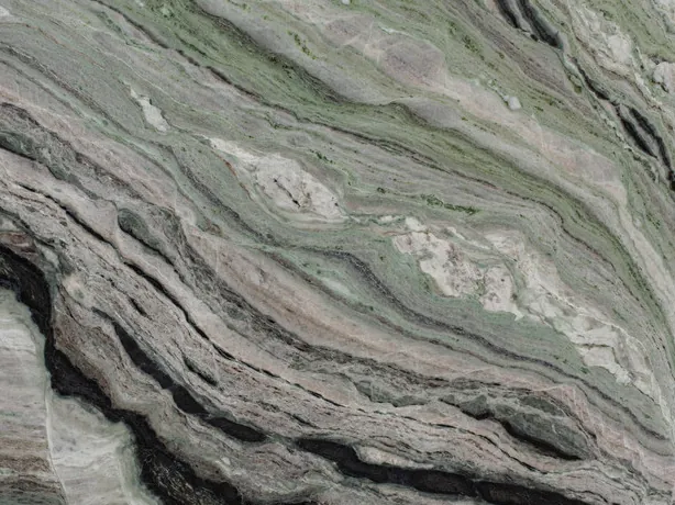 Detail of green Camellia Green marble: dense bands and polished shine over the greyish green