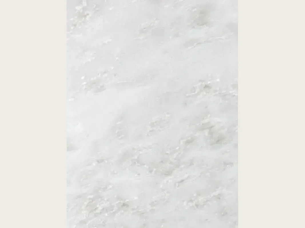 Slab of white Namibia Cream marble: an almost plain grayish white background with faint gray clouds on the diagonal
