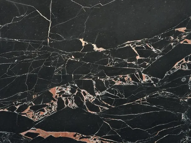 Close-up of black Orange Black marble: salmon-orange spots and fine white veins over the polished black