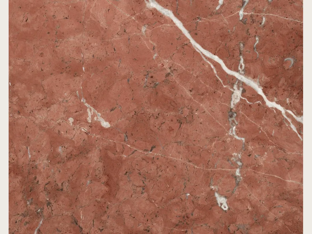 Rojo Alicante marble slab: an even terracotta red background with a few diagonal white veins and small dark flecks