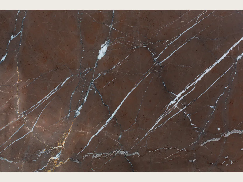 Rosso Collemandina marble slab: a dark reddish brown background with fine white veins running diagonally