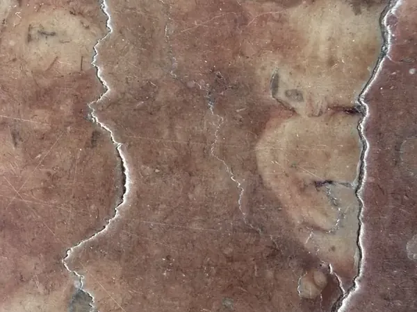 Chapa de Mármore Rosso Verona: fundo vermelho arroxeado com nuvens bege e dois veios brancos verticais