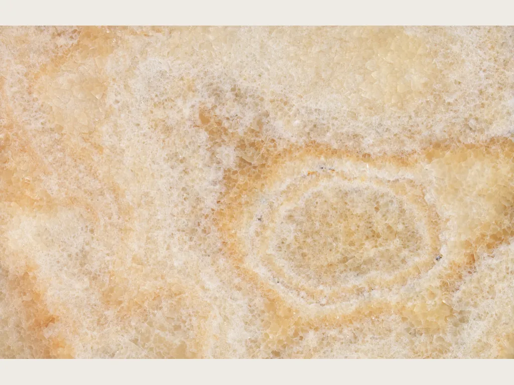 Yellow onyx slab: diffuse clouds in honey and cream over a light background, with the oval ring on the right