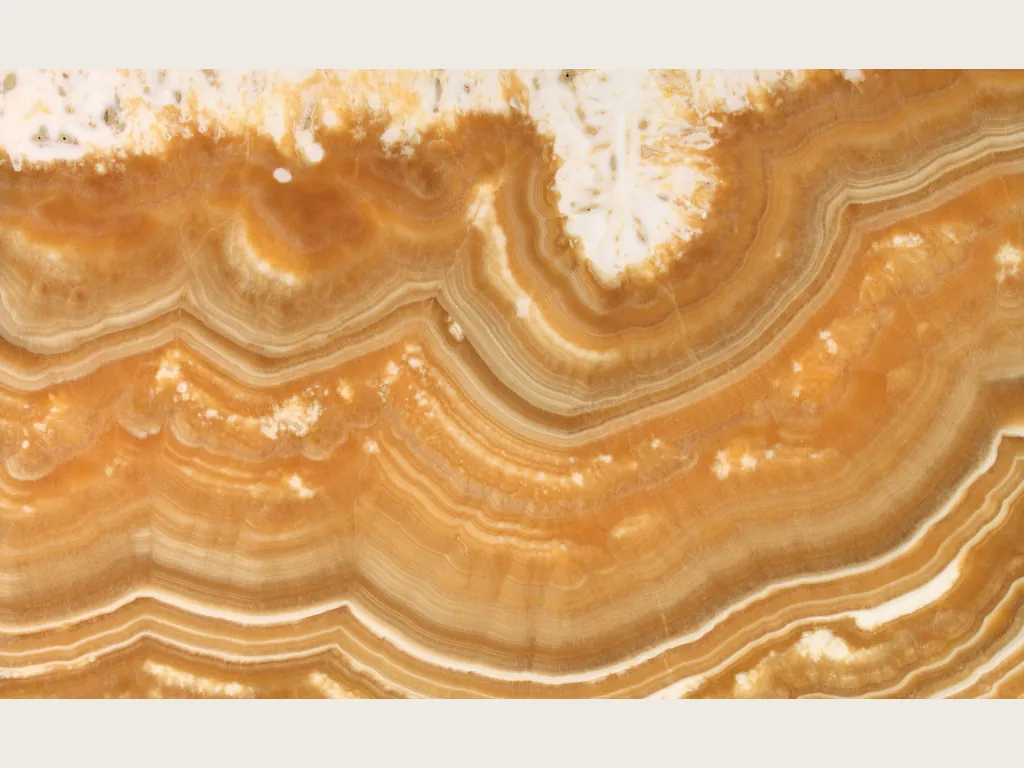 Slab of orange Arancio onyx: wavy orange and amber bands under a crystalline white area