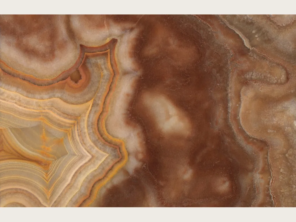 Sultano brown onyx slab: concentric orange and cream rings on a reddish brown background