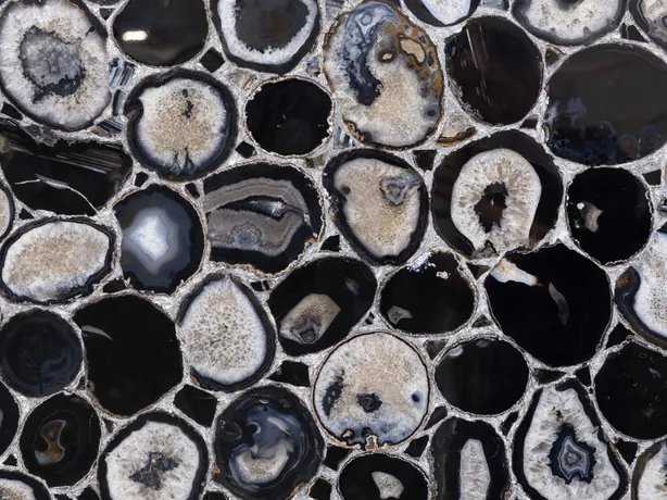 Close-up of black agate with silver leaf: the gray and white rings of the slices and the silver joints with the gloss of the polish