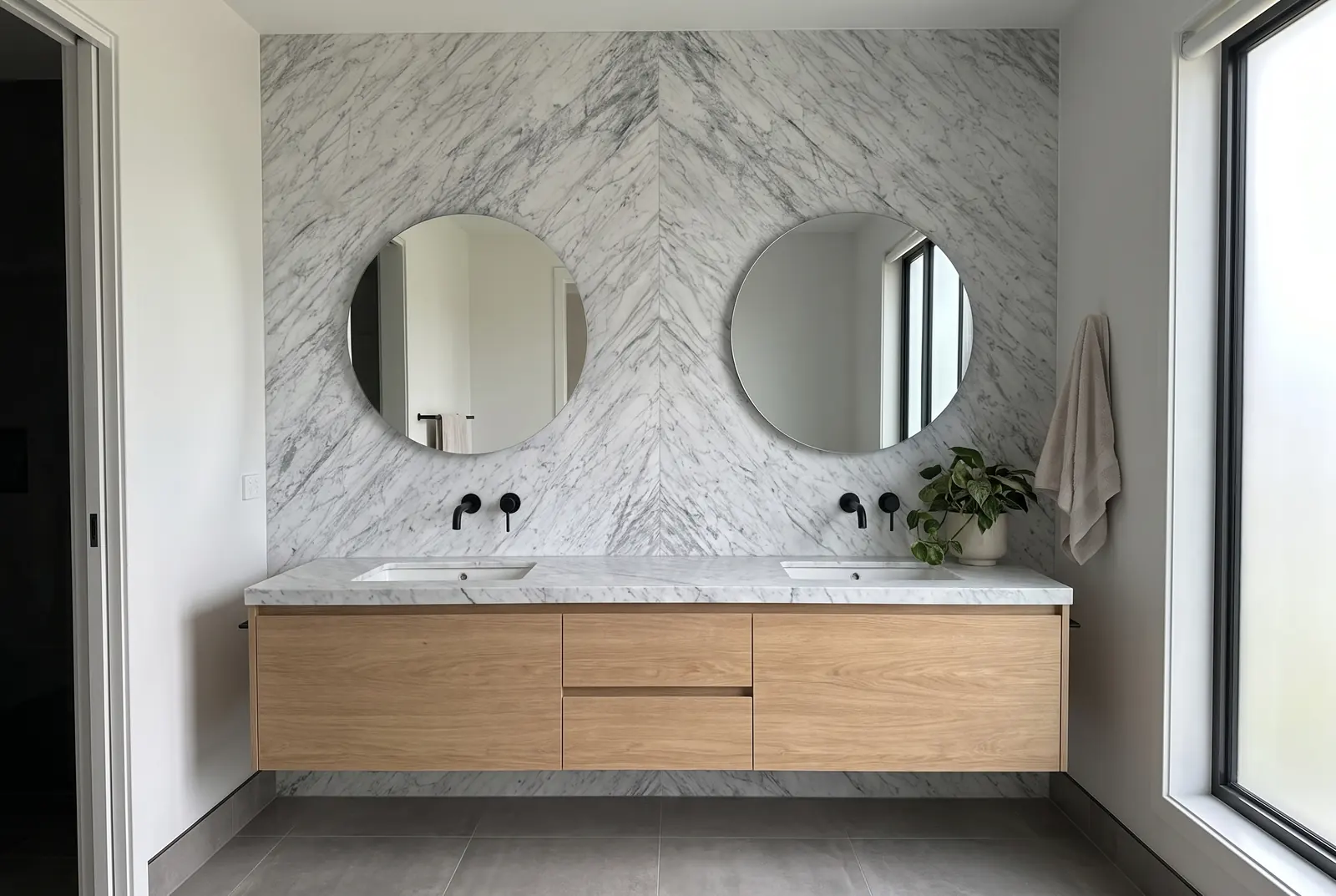 Bathroom with the vanity wall in two bookmatched Carrara marble slabs and an oak vanity