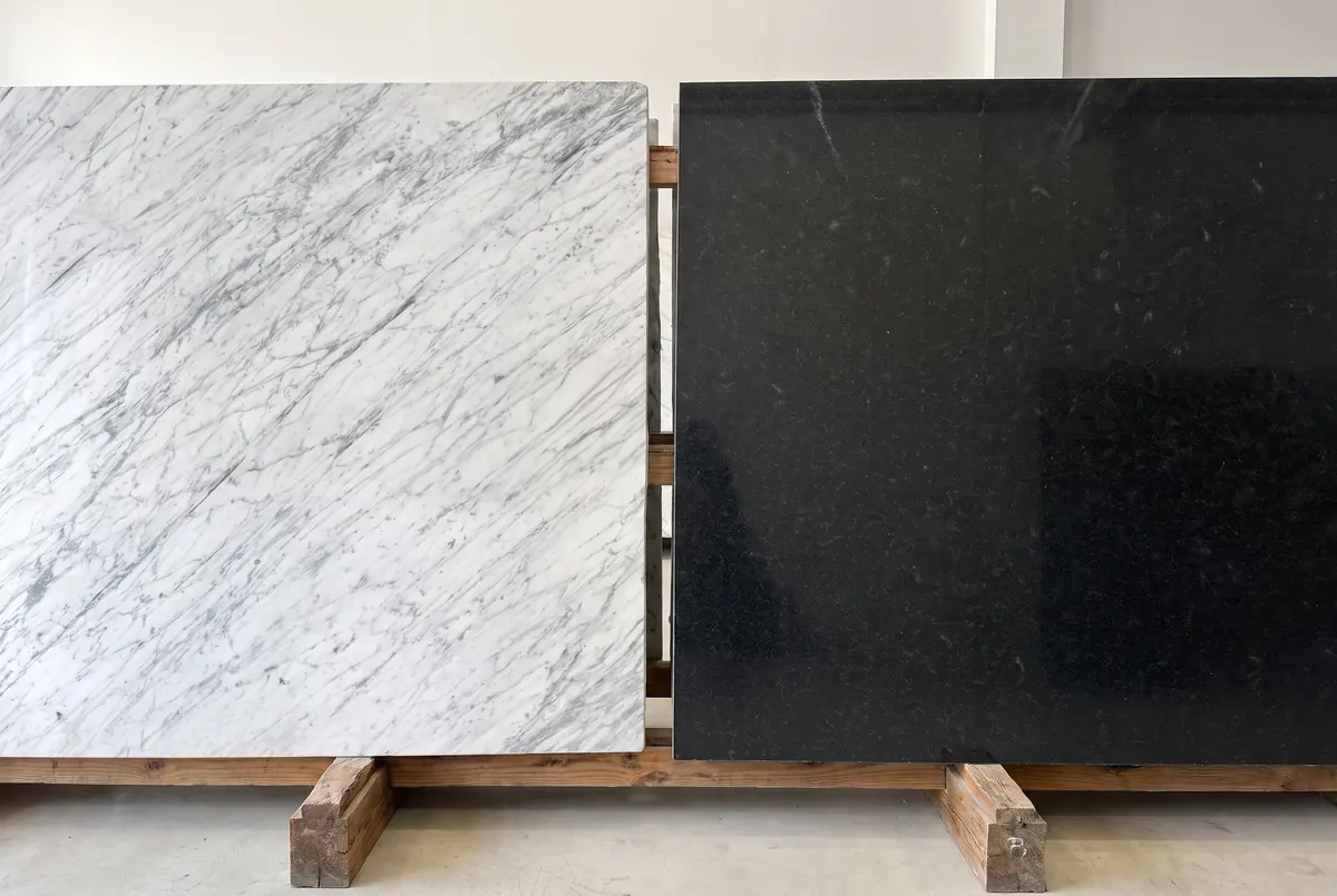 A white marble slab and a black granite slab side by side in the same light