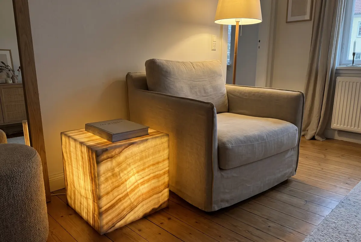 Cube-shaped honey onyx side table lit from within, next to an armchair