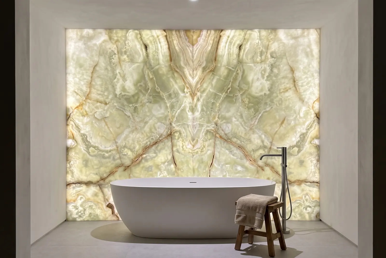 Bathroom wall of backlit green onyx behind a freestanding bathtub